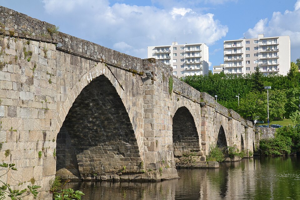 Le pont Saint-Martial à Limoges : arches de granit médiévales et leurs avant-becs plongeant dans la Vienne, immeubles blancs et arbres sur la rive opposée
